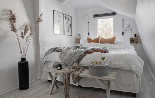O banco na frente da cama é uma opção multifuncional para este quarto pequeno O banco na frente da cama é uma opção multifuncional para este quarto pequeno
